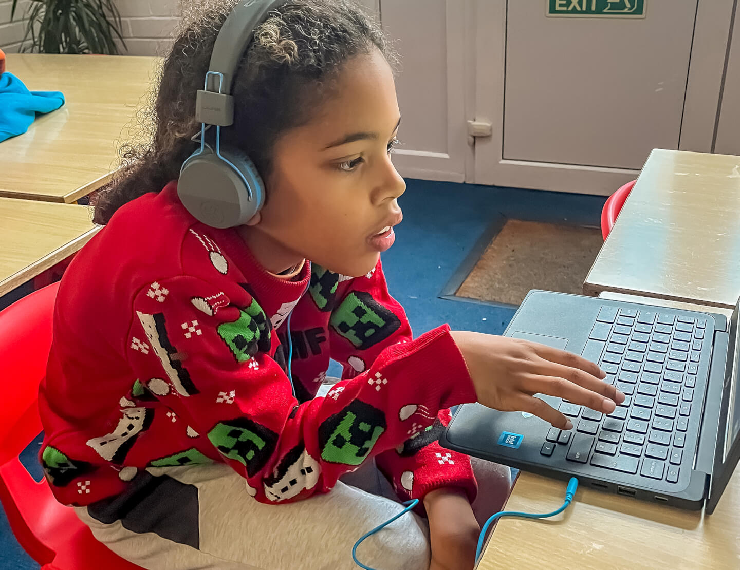 Child wearing headphones while using laptop